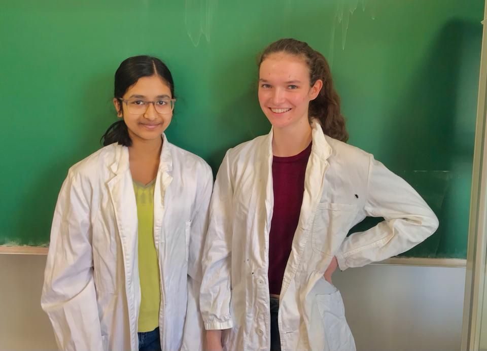 Zwei Schülerrinnen stehen vor einer Tafel