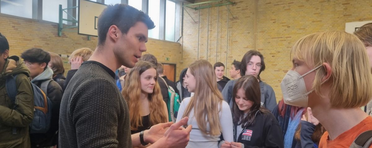 mehrere Schüler unterhalten sich in einer Turnhalle