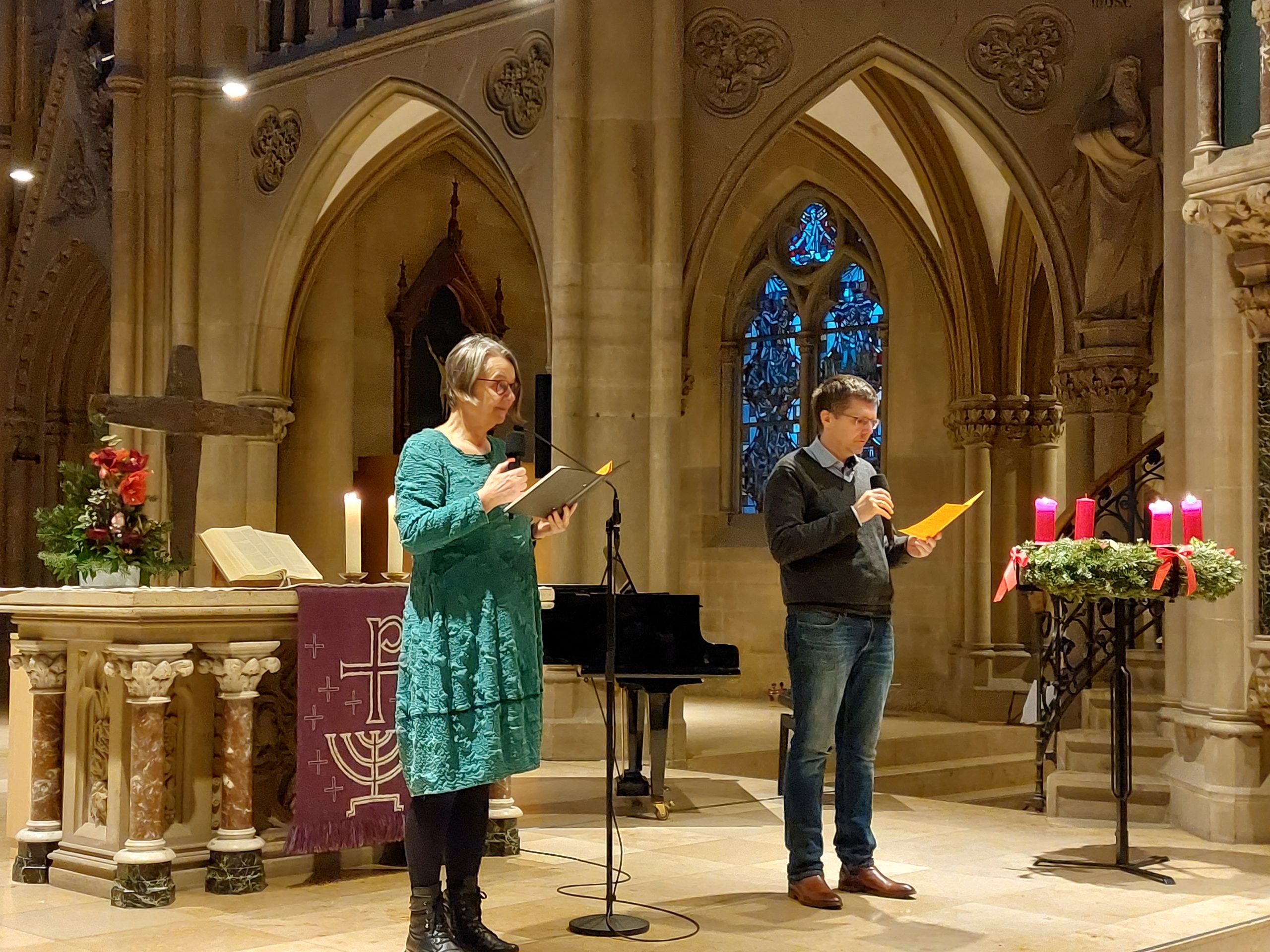 2 Personen mit einem Mikrofon stehen vor einem Altar