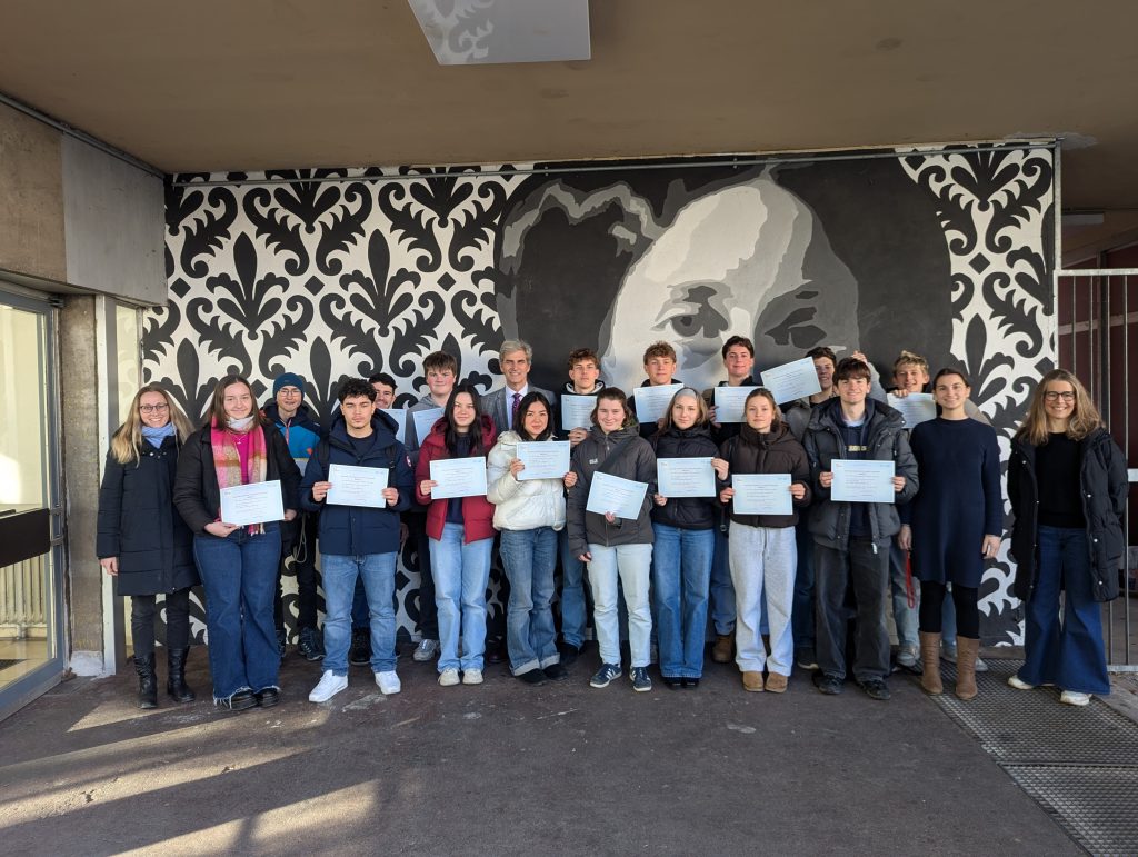 Schüler stehen vor einer Wand und halten ihre DELF Zertifikate