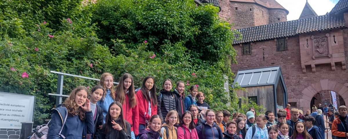 Mehrere Personen posieren für ein Gruppenbild vor einer Burg