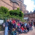 Mehrere Personen posieren für ein Gruppenbild vor einer Burg