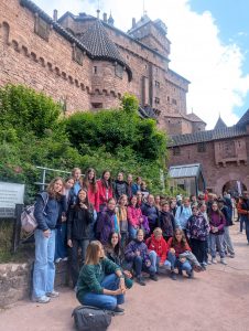 Mehrere Personen posieren für ein Gruppenbild vor einer Burg