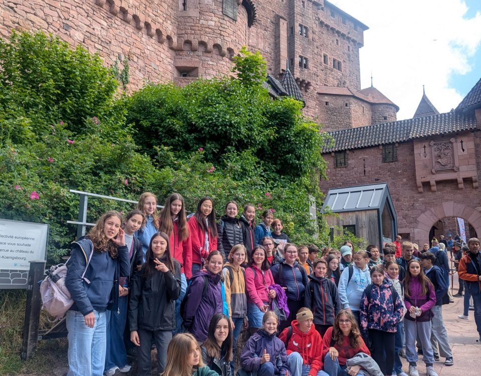 Mehrere Personen posieren für ein Gruppenbild vor einer Burg