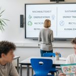 Man sieht einen Lehrer der auf einen großen Bildschirm schaut